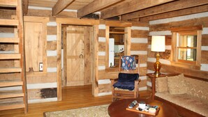A log cabin interior with a wooden floor, a sofa, a chair, a table, and a lamp. - Peace Cabin- 20 min hike to Wilson Cave! (Deputy)