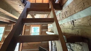 A wooden interior with a central wooden staircase, wooden walls, and a window with a view. - Peace Cabin- 20 min hike to Wilson Cave! (Deputy)