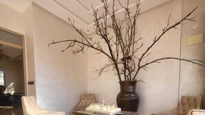 Eine geräumige Lobby mit Marmorböden, einer großen Vase mit Zweigen und zwei Ledersesseln.
