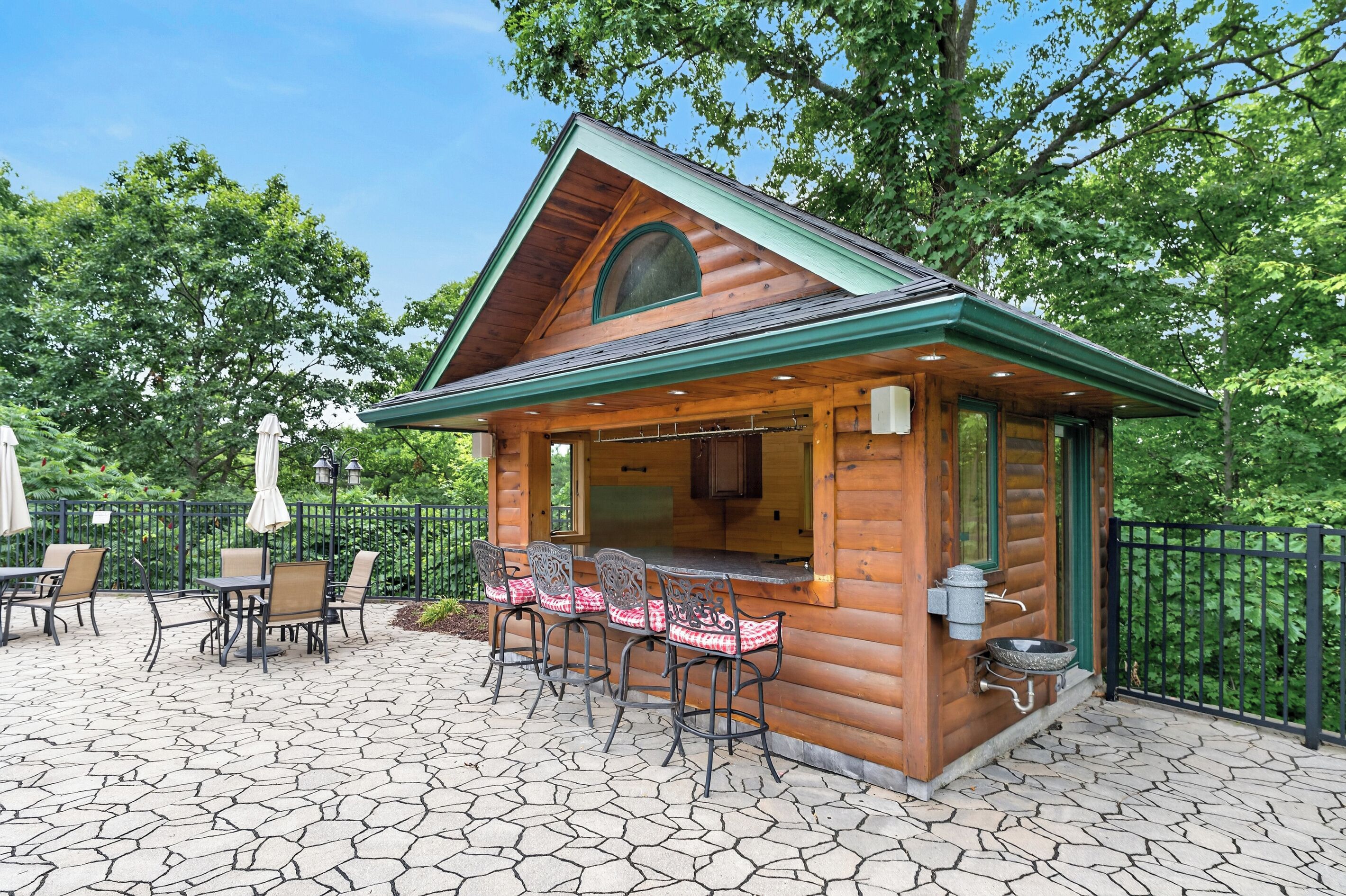 A wooden cabin with a patio area featuring outdoor seating and a bar.