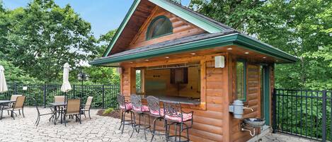 A wooden cabin with a patio area featuring outdoor seating and a bar.