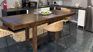 A modern kitchen with white cabinets, a wooden dining table, wicker chairs, a microwave, and a coffee maker. - Peaceful studio with AC in charming El Paso (El Paso)