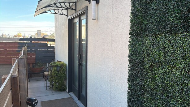 A balcony with a wooden railing, a small table with chairs, a potted plant, and a door with a glass panel. - Peaceful studio with AC in charming El Paso (El Paso)