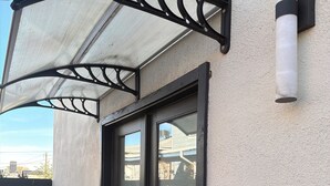 A building entrance with a black door, a mesh awning, and a potted plant. - Peaceful studio with AC in charming El Paso (El Paso)