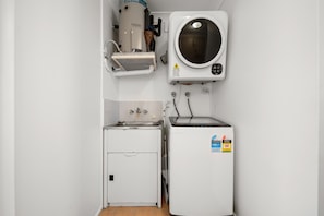 Eine kleine Küche mit Einbauwaschmaschine, Spüle und kompaktem Kühlschrank.