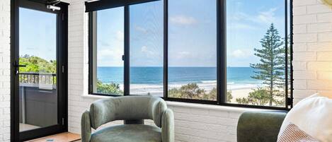A room with a large window offering a view of the ocean and a white brick wall.