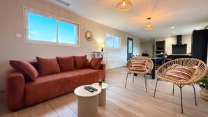 Ein modernes Wohnzimmer mit einer Couch, zwei Sesseln, einem runden Couchtisch und Pendelleuchten.