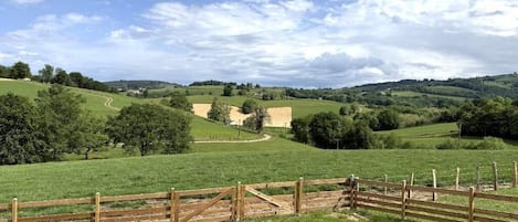Un paysage rural avec des collines douces, une clôture en bois et un ciel dégagé.