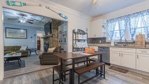 Eine moderne Küche mit Essbereich, Kamin aus Stein und Blick zum Wohnzimmer.