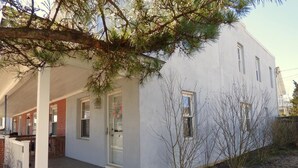 A white building with a covered porch and a small garden area. - Renovated 3BR Shore House • Yard, Porch & Bay Breezes • Pet Friendly (Ocean City)
