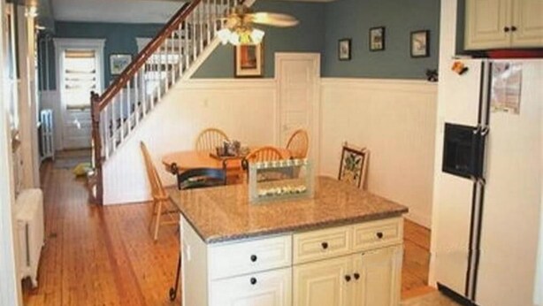 A kitchen with a central island, white cabinetry, a ceiling fan, and a staircase leading to another room. - Renovated 3BR Shore House • Yard, Porch & Bay Breezes • Pet Friendly (Ocean City)