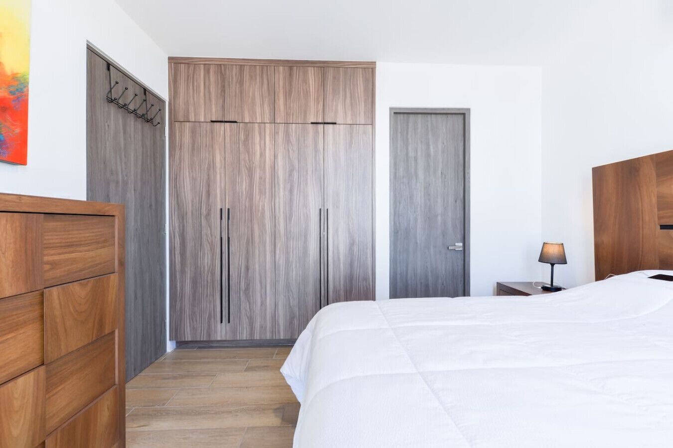 A bedroom with a bed, wooden wardrobe, and a door.