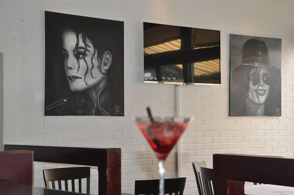 A restaurant interior with white brick walls, black and white artwork, and a martini glass on a table. - Comfort Hotel Egerkingen (Egerkingen)
