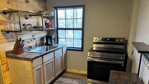 A kitchen with wooden cabinets, a stainless steel oven, a coffee maker, and a window.