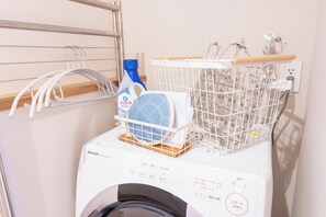 A front-loading washing machine with a basket of clothes and a blue detergent bottle. - Hakone Seiun (Hakone)