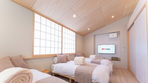 A hotel room with two beds, a large window, a YouTube screen, and a wooden ceiling. - Hakone Seiun (Hakone)