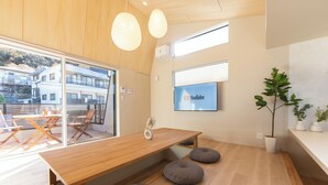 A modern interior with a wooden table, grey poufs, a YouTube screen, and a potted plant. - Hakone Seiun (Hakone)