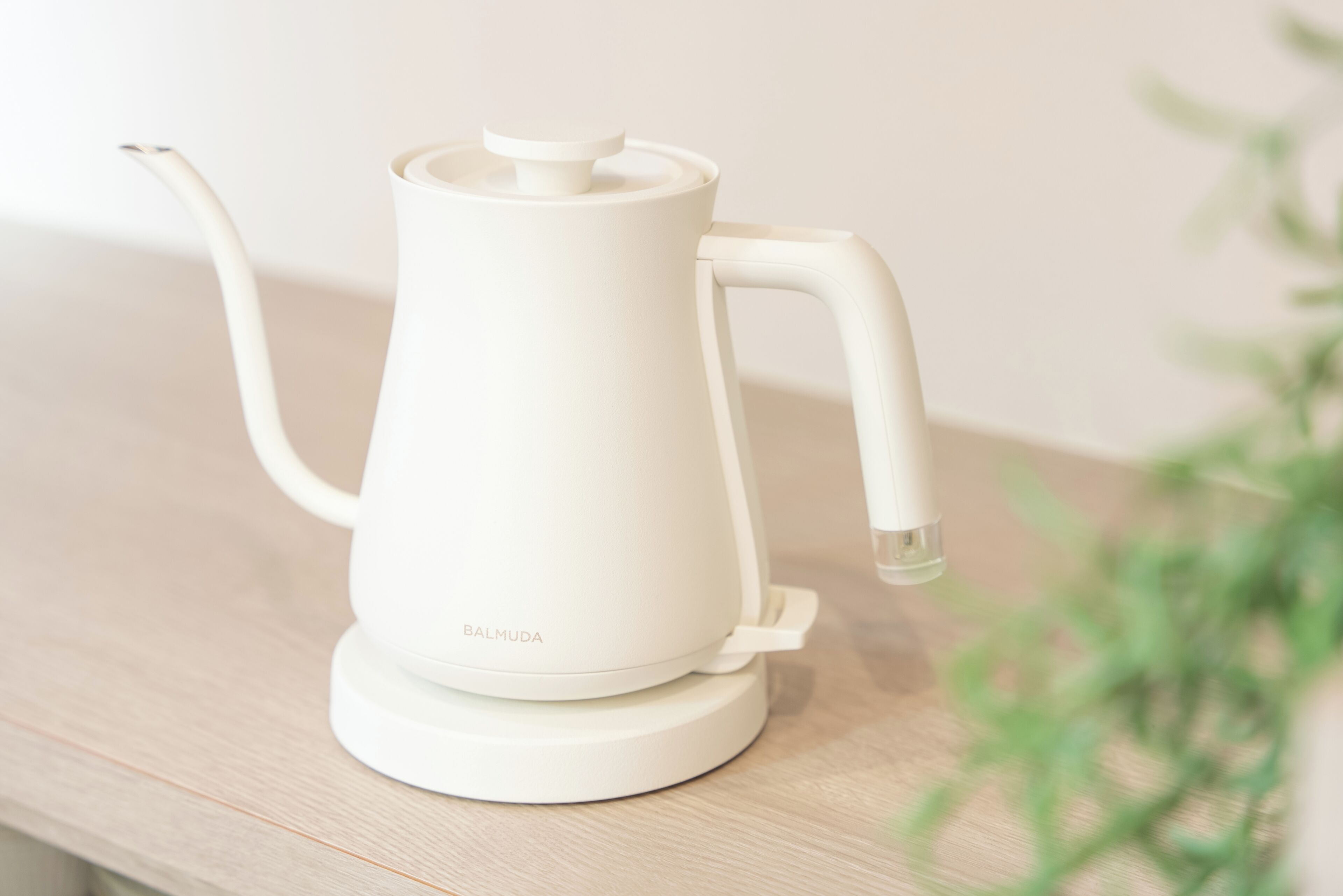 A white electric kettle on a wooden surface.