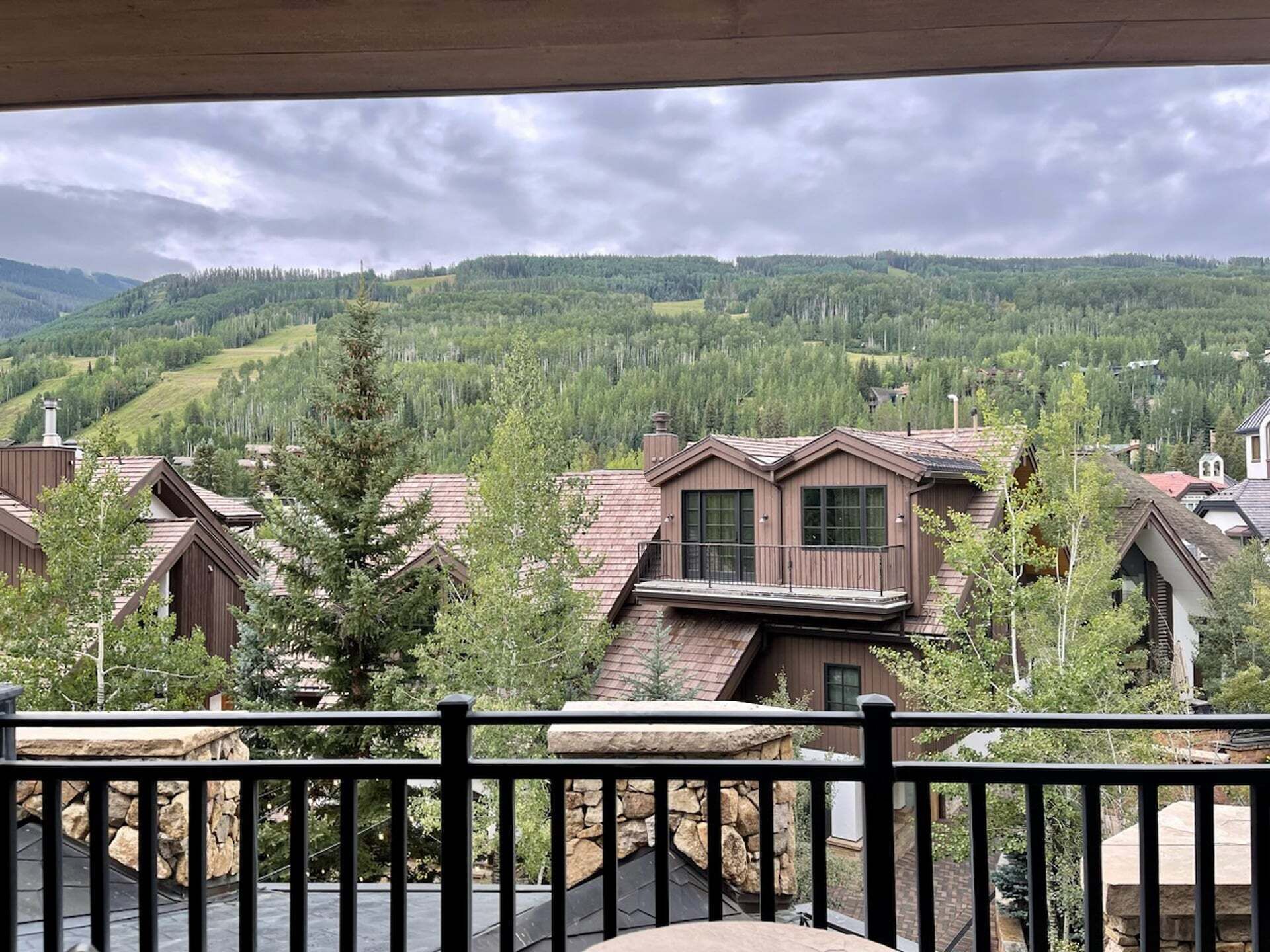 A residential area with houses, a stone wall, and a view of a forested hillside.