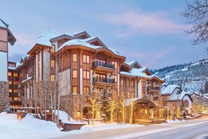 A large, multi-story lodge with a snow-covered roof, a stone facade, and a prominent entrance with a covered porch. - Vail Village Location, 5 Star Services & Amenities + Ski In/Out Base Camp (Vail)