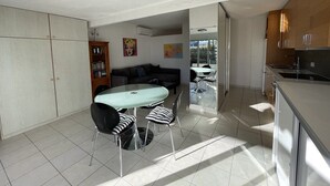 Eine moderne Küche mit Essbereich, einer Couch und Blick durch eine Glastür.
