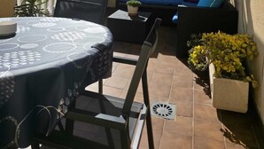 A covered patio with a round table, chairs, a sofa with cushions, potted plants, and a view of the sky. - Penthouse city sea and sun (Torrevieja)