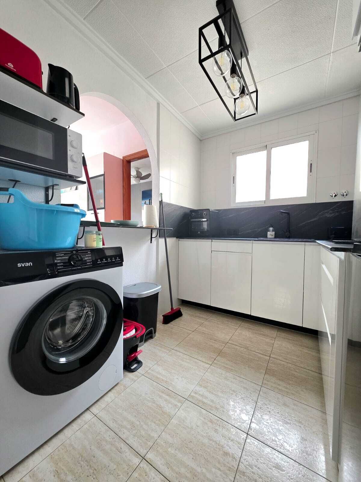 A compact kitchen with a washing machine, a microwave, and a coffee machine.