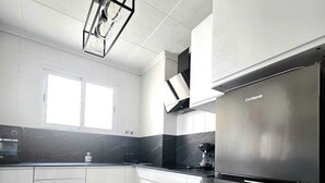 A modern kitchen with white cabinets, a stainless steel refrigerator, and a black countertop. - Penthouse city sea and sun (Torrevieja)