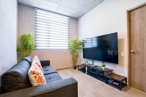 A modern living room with a sofa, TV, and plants.