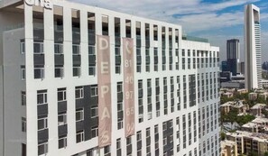 A modern high-rise building with multiple floors, large windows, and banners with numbers.