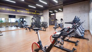 Un gimnasio con equipo de ejercicio, frases motivacionales en la pared y suelo de madera.