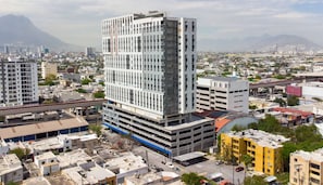 A multi-story building with a modern architectural design, surrounded by a cityscape with various buildings and a mountain in the background. - ¡A pasos de Fundidora! 5 huéspedes, Seguridad 24/7 (Monterrey)