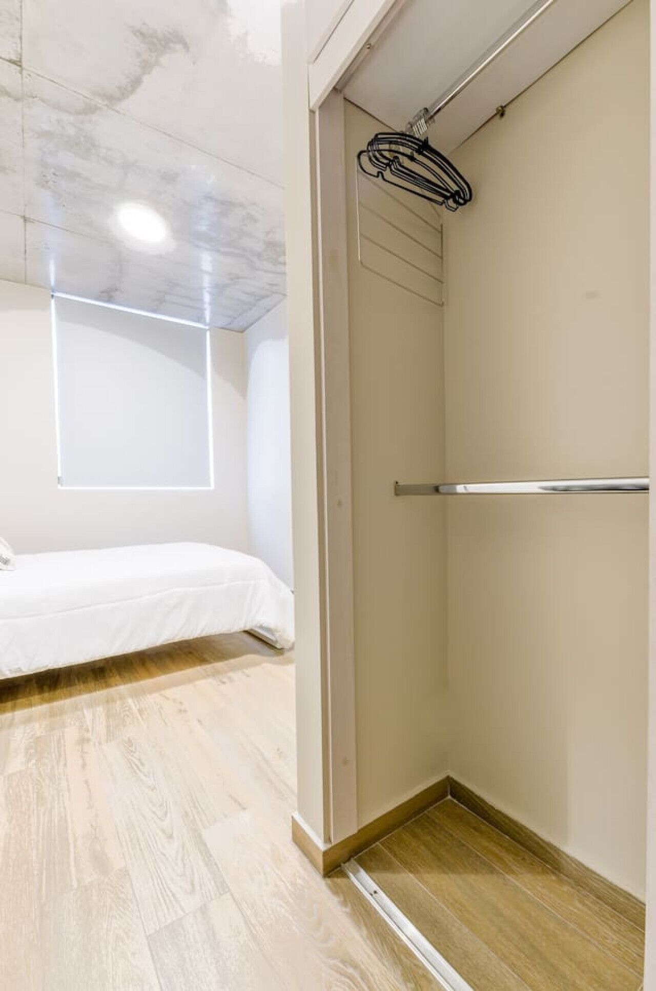 Ein Zimmer mit einem Bett, einer Duschkabine mit Handtuchhalter und Holzboden.