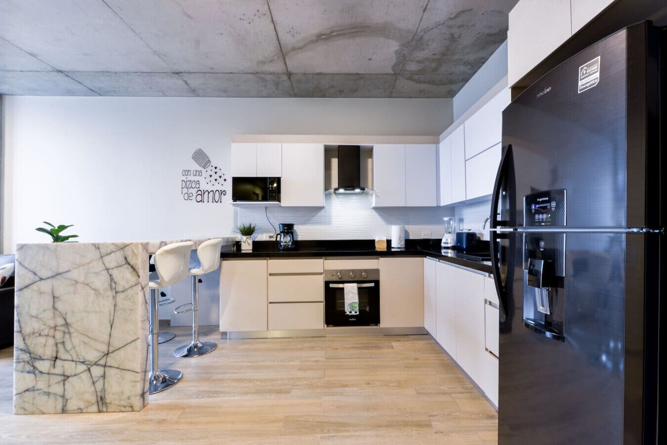 A modern kitchen with a marble island, stainless steel appliances, and a built-in oven.