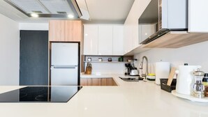 Una cocina moderna con horno empotrado, un lavamanos y una cafetera.