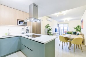Eine moderne Küche mit einer zentralen Kochinsel, eingebauten Geräten und einem Essbereich mit Tisch und Stühlen.