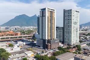 A high-rise building with a modern design, a prominent sign, and a mountain in the background. - ¡A pasos de Paseo Santa Lucía! - Cama King + Wifi (Monterrey)