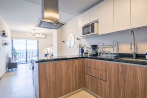 Eine moderne Küche mit Kochinsel, Edelstahlgeräten und Blick auf einen Balkon.