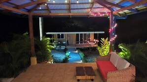 An outdoor patio area with a tiled floor, a red sofa, and a wooden bench. - Lovely ,1 Bedroom house , Sunset view from pool, Monkeys ! 20 mins to Tamarindo  (Guanacaste Province)