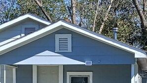 A single-story house with a front porch, a door, a window, and a small table with chairs.