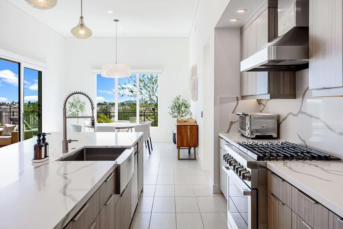 A modern kitchen with a large island, stainless steel appliances, and a view of the outdoors.