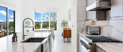 Una cocina moderna con una isla grande, electrodomésticos de acero inoxidable y vistas al exterior.