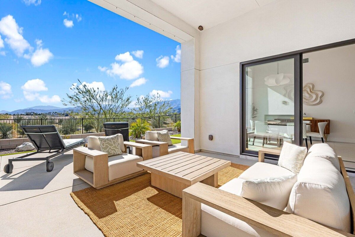 Un espacio exterior moderno con sala, sillas y una mesa.