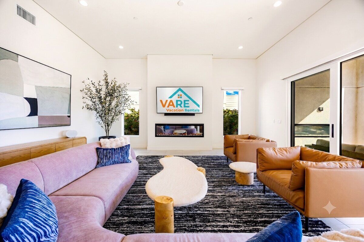 A modern living room with a sofa, armchairs, a coffee table, and a TV screen displaying a logo.
