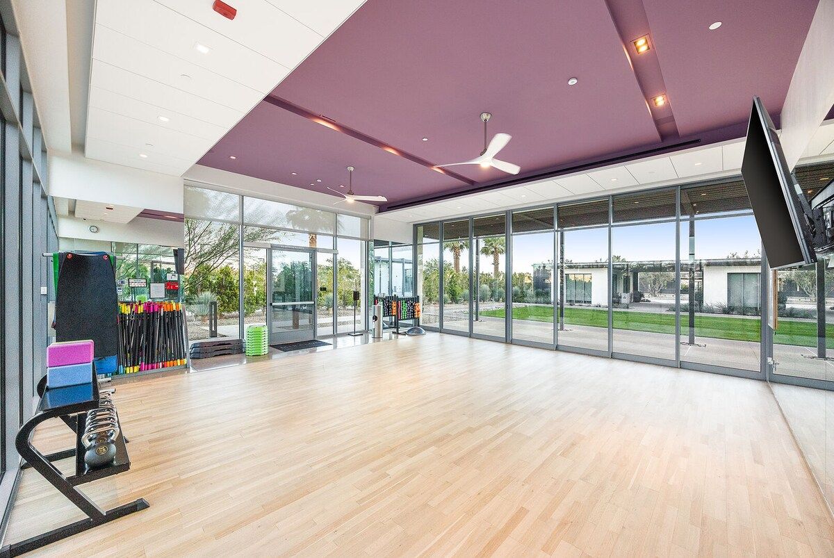 A spacious indoor area with a large window, ceiling fans, and exercise equipment.