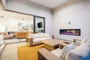 A modern living room with a fireplace, sofas, and a coffee table. - Golden Hour by VARE | Miralon Resort! (Palm Springs)