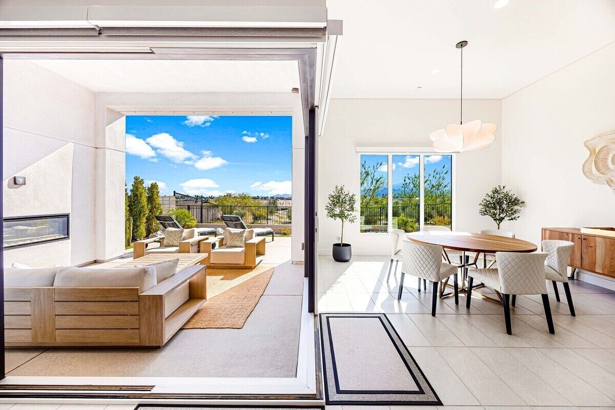 Un interior moderno con comedor, zona de estar con sofás y vistas al exterior.
