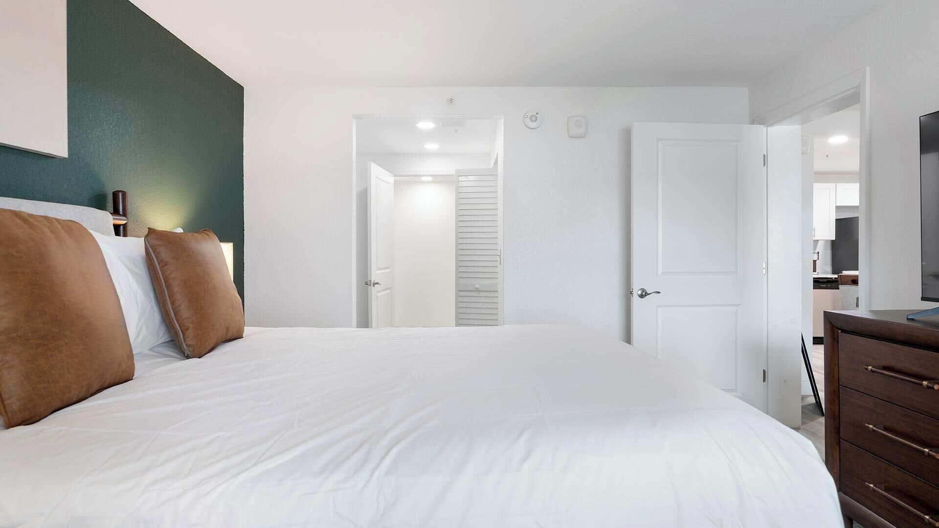 A bedroom with a bed, a dresser, and a television.