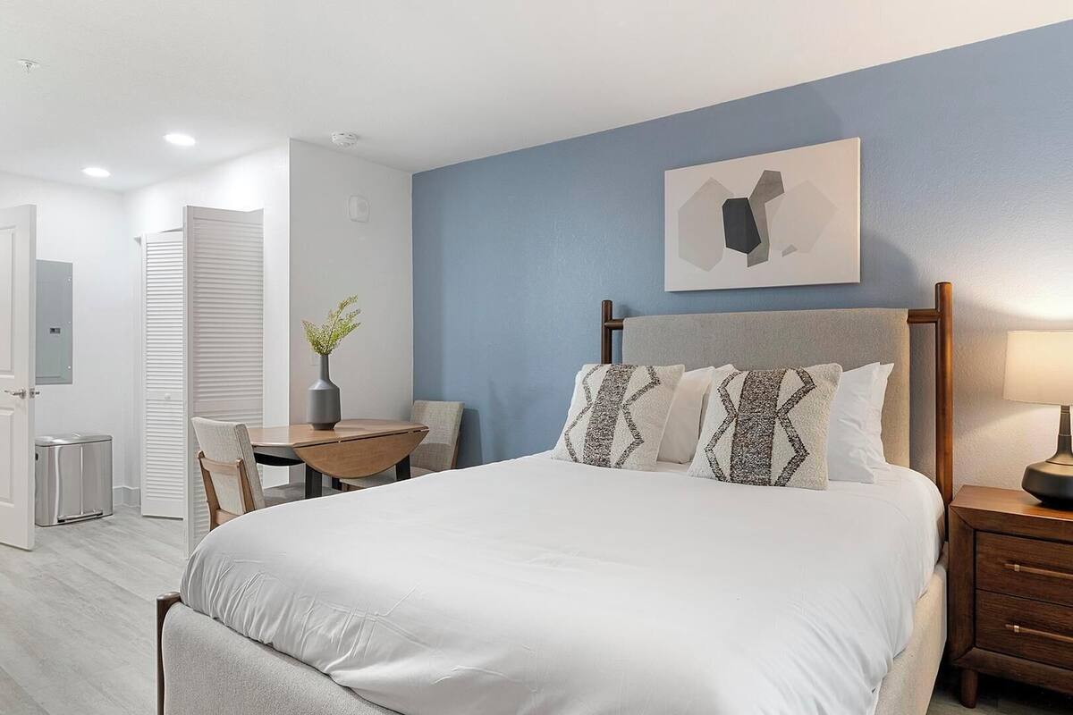 Une chambre à coucher avec un lit, des tables de chevet, un bureau et une chaise.