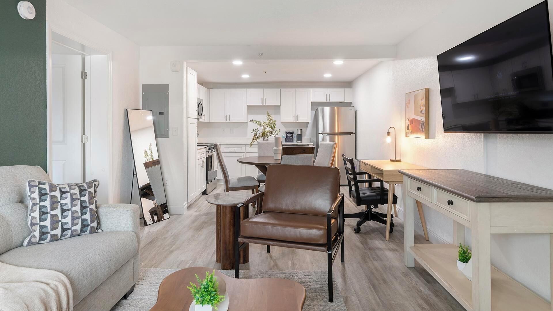 Een modern appartement met een woonkamer, eetgedeelte, keuken en een aan de muur bevestigde televisie.